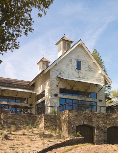 Rustic stone and wood building with large windows and a weathered facade, nestled in a tranquil woodland setting.