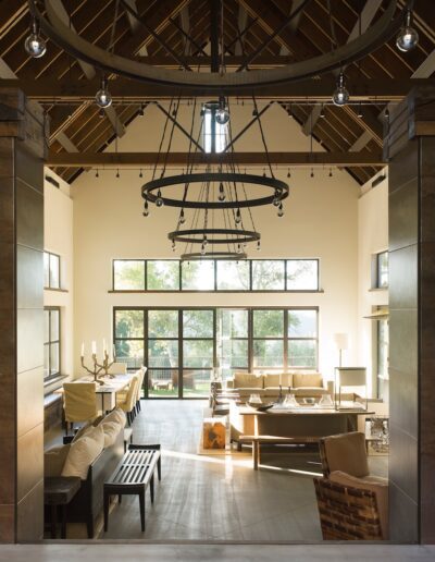 Spacious living room with high ceilings, large windows, and a central chandelier.
