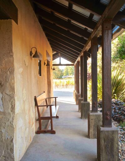 A serene porch with wooden columns and a rocking chair overlooking a garden.